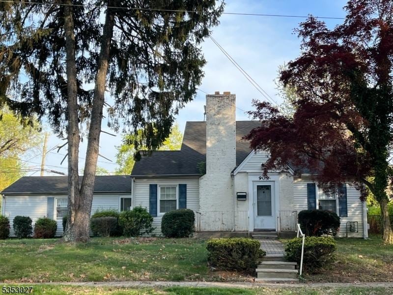 view of front of house featuring a chimney and a front lawn