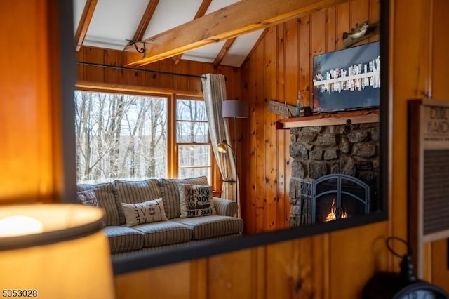 living area with wood walls, a fireplace, and vaulted ceiling with beams