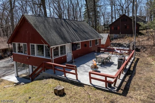 rear view of house with roof with shingles, stairs, and a patio