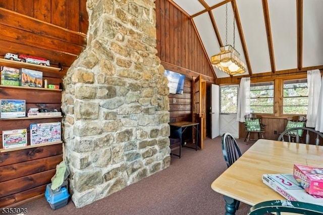 dining space with wood walls, carpet, and high vaulted ceiling