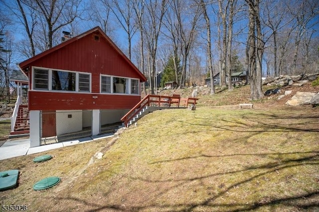 view of property exterior featuring a lawn, stairway, a chimney, and a wooden deck