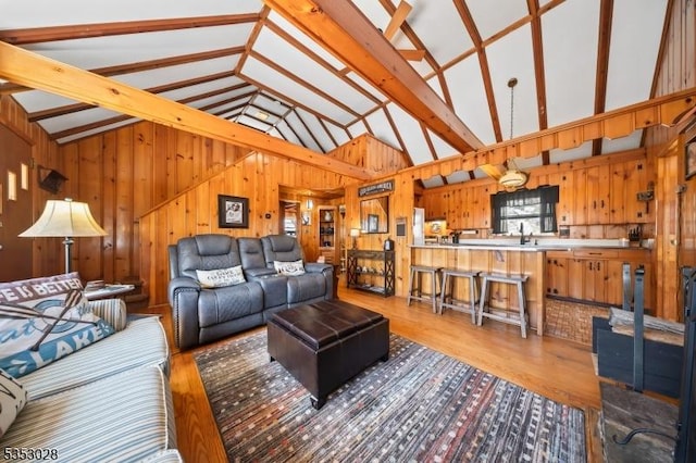 living room featuring wood walls, wood finished floors, and high vaulted ceiling