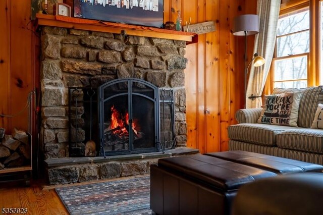 living area with wood finished floors and a stone fireplace