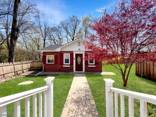 bungalow-style home featuring a front yard, fence private yard, and brick siding