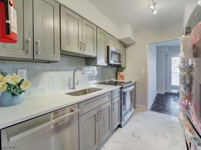 kitchen featuring stainless steel appliances, light countertops, marble finish floor, and a sink