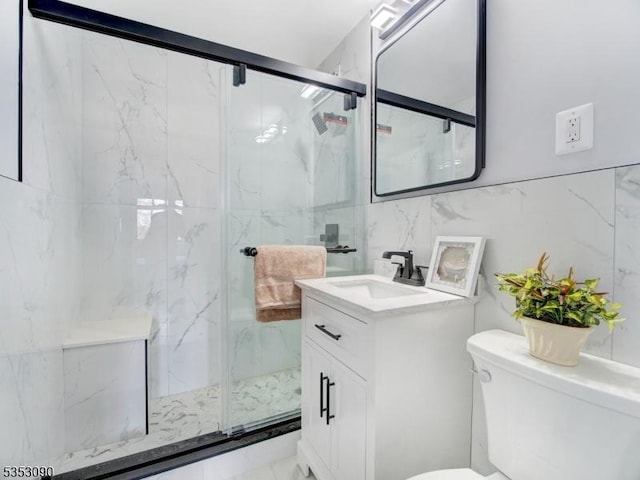 bathroom with tile walls, vanity, toilet, and a marble finish shower