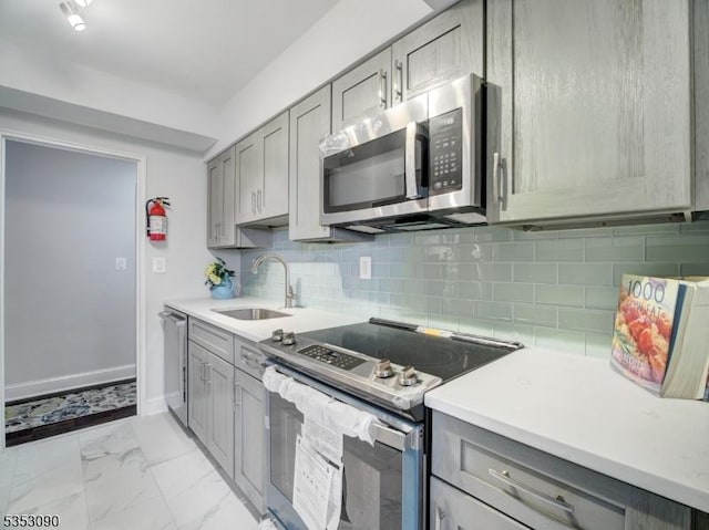kitchen featuring appliances with stainless steel finishes, gray cabinetry, and a sink
