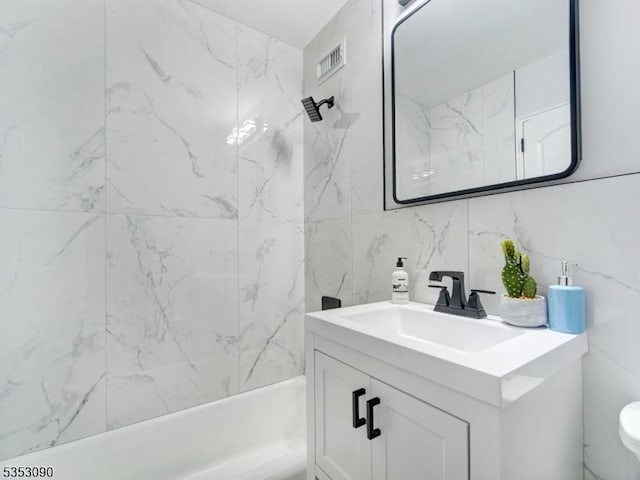 full bathroom featuring visible vents, toilet, tile walls, vanity, and bathtub / shower combination