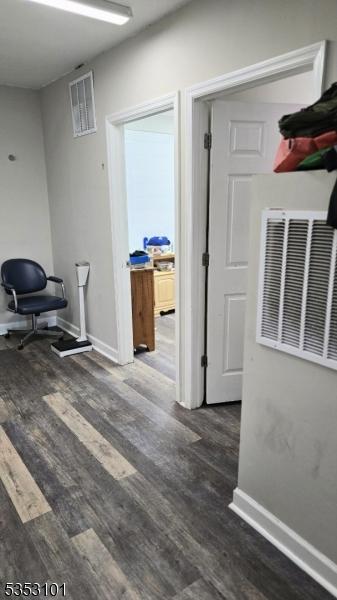 corridor featuring visible vents, baseboards, and wood finished floors