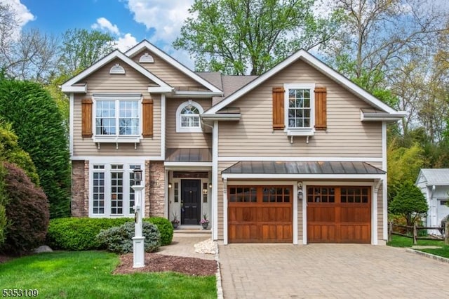 craftsman-style house featuring decorative driveway, a standing seam roof, metal roof, and a garage