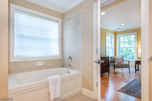 bathroom with baseboards, ornamental molding, a garden tub, and wood finished floors