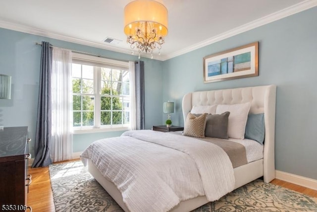 bedroom featuring visible vents, ornamental molding, an inviting chandelier, wood finished floors, and baseboards