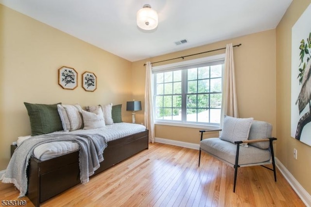 bedroom with baseboards, hardwood / wood-style flooring, and visible vents