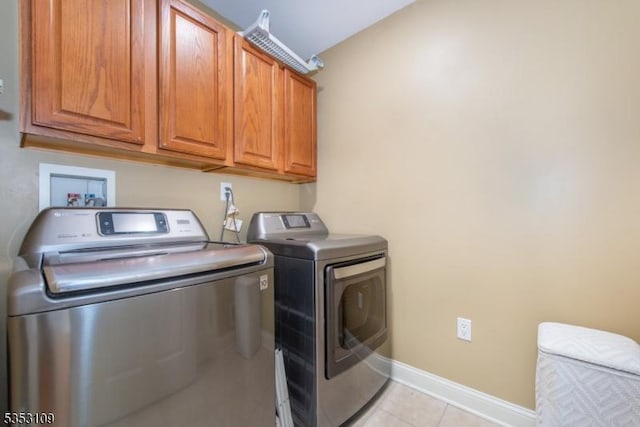 laundry area featuring baseboards, cabinet space, light tile patterned flooring, and washing machine and clothes dryer
