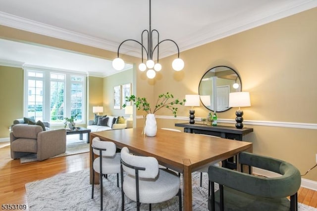dining space with crown molding, light wood-style floors, baseboards, and an inviting chandelier