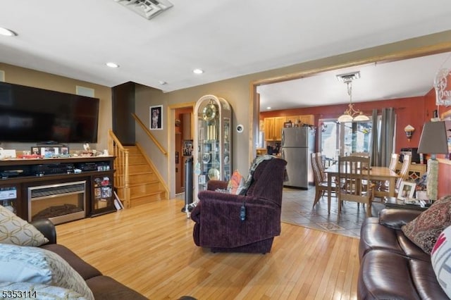living area with visible vents, light wood-type flooring, stairs, and recessed lighting