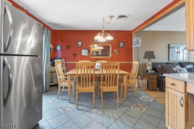 dining area with an inviting chandelier, light tile patterned floors, and visible vents