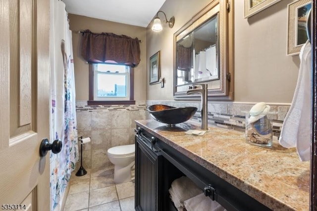 full bath with tile patterned floors, tile walls, a wainscoted wall, toilet, and vanity
