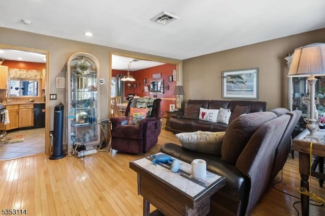 living area with visible vents, light wood-type flooring, and a chandelier