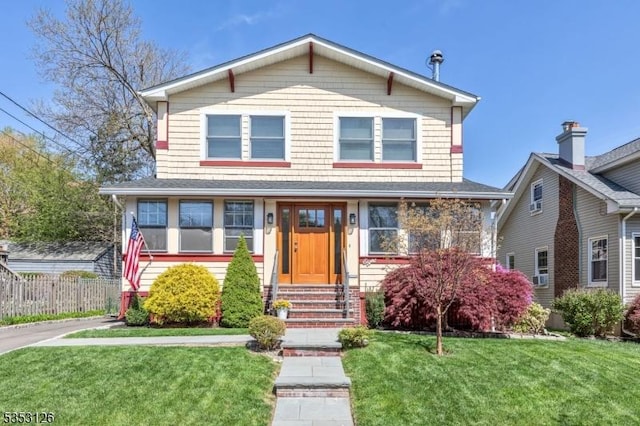 view of front of property with fence, entry steps, and a front lawn