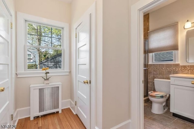 doorway with light wood finished floors and radiator heating unit