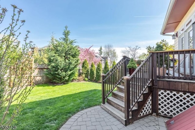 view of yard with a fenced backyard, a wooden deck, and stairway