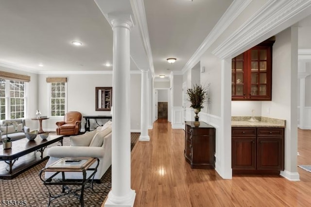 corridor with ornate columns, recessed lighting, light wood-style flooring, and crown molding