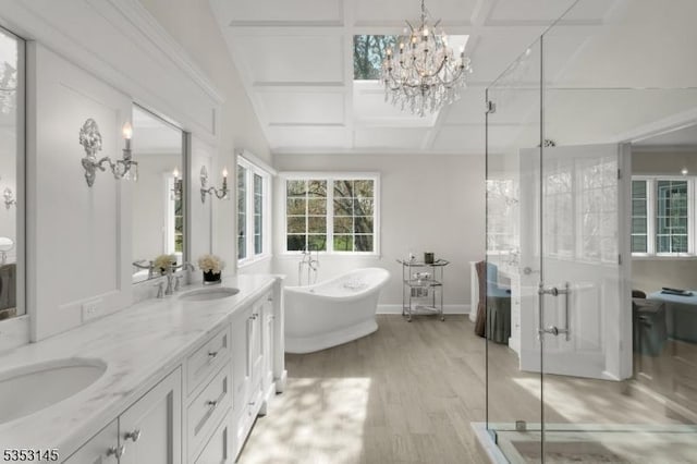 bathroom featuring a notable chandelier, a sink, a freestanding tub, a shower stall, and wood finished floors