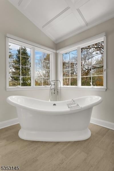 bathroom with baseboards, vaulted ceiling, and a freestanding tub