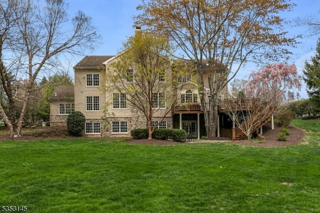 back of property with a yard, a deck, a chimney, and stone siding