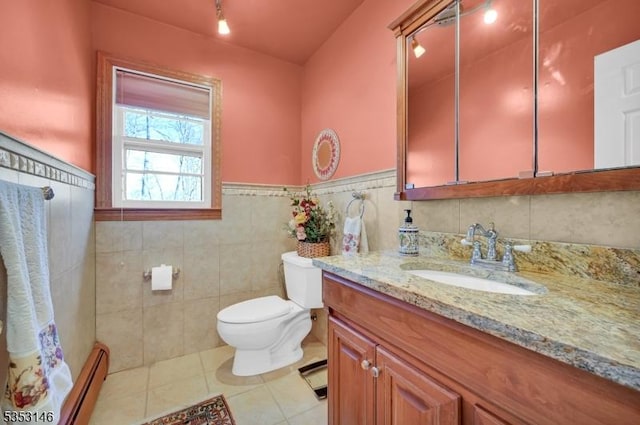 bathroom with baseboard heating, vanity, toilet, tile patterned floors, and a wainscoted wall