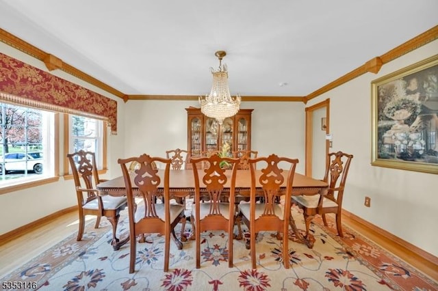 dining area with crown molding, baseboards, an inviting chandelier, and light wood finished floors