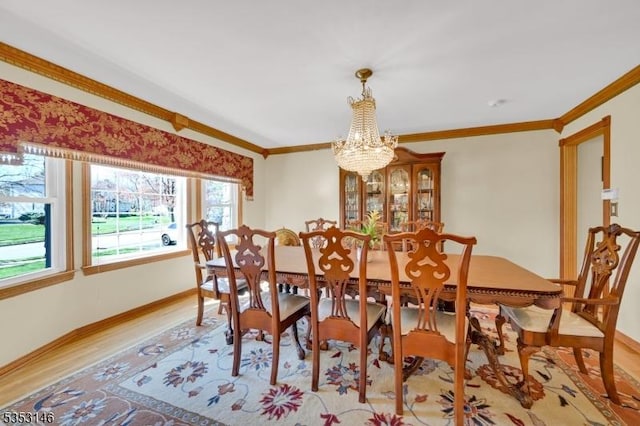 dining room with baseboards, ornamental molding, wood finished floors, and a notable chandelier