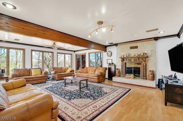 living area featuring visible vents, plenty of natural light, a high end fireplace, and light wood-type flooring