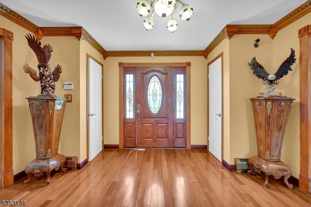 foyer featuring crown molding, baseboards, an inviting chandelier, and light wood-style floors