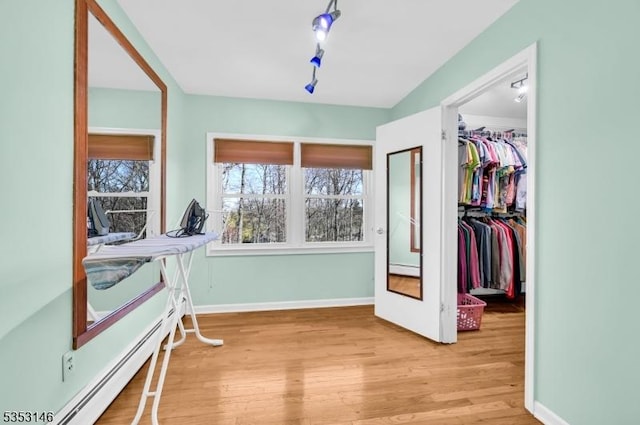 interior space with a walk in closet, wood finished floors, baseboards, a closet, and a baseboard heating unit