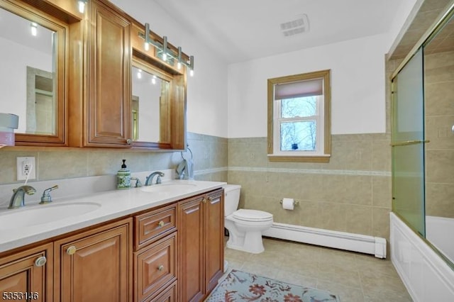 bathroom with tile walls, baseboard heating, a sink, tile patterned floors, and toilet