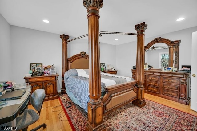 bedroom with decorative columns, recessed lighting, and light wood-style flooring