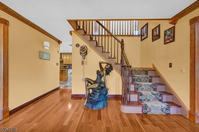 staircase with crown molding, baseboards, and wood finished floors