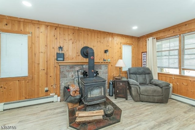 living area with baseboard heating, a wood stove, wood walls, wood finished floors, and recessed lighting