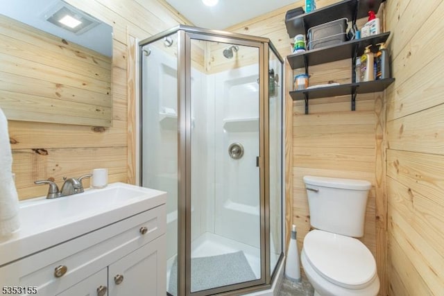 bathroom with vanity, wood walls, toilet, and a shower stall