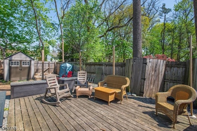 wooden terrace featuring a fenced backyard, a storage unit, and an outbuilding