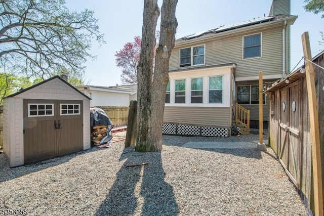 rear view of house with fence, an outdoor structure, entry steps, and a storage unit