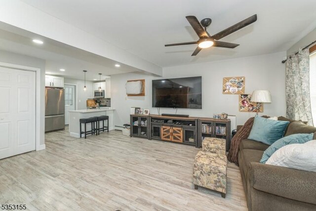 living room featuring ceiling fan, recessed lighting, and light wood-style flooring