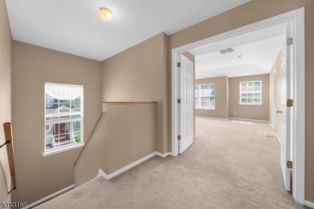 corridor featuring light colored carpet, baseboards, visible vents, and an upstairs landing