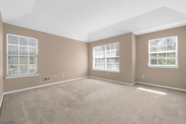 unfurnished room featuring a wealth of natural light, carpet, and visible vents