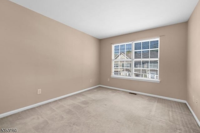 empty room featuring baseboards, visible vents, and light colored carpet