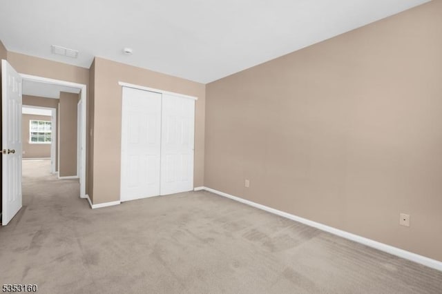 unfurnished bedroom featuring baseboards, visible vents, light carpet, and a closet