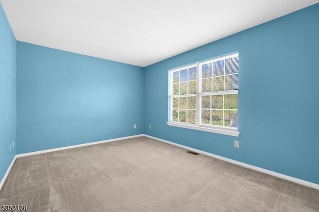 carpeted empty room featuring baseboards and visible vents