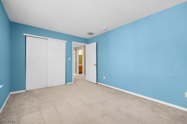 unfurnished bedroom featuring visible vents, baseboards, carpet floors, and a closet